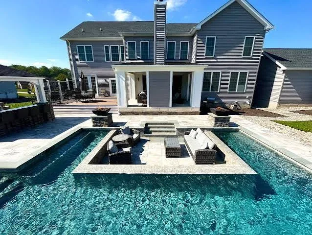 Saltwater pool, spa, and fire pit island with travertine decking and seating area