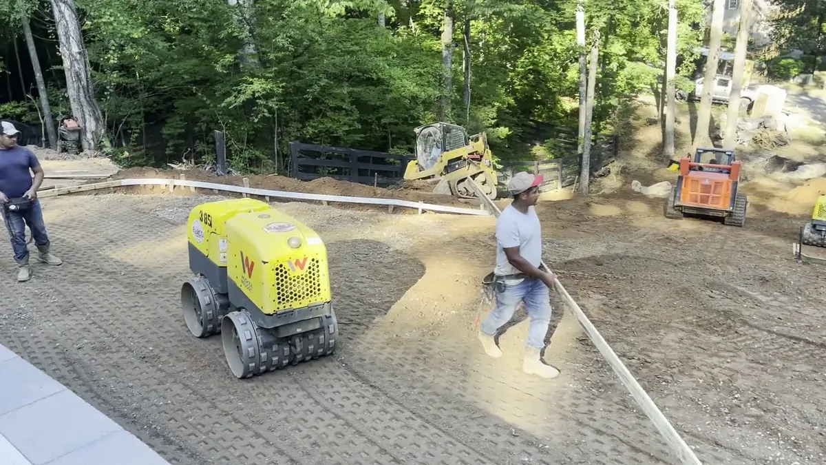 Crew grading and compacting the base for a patio