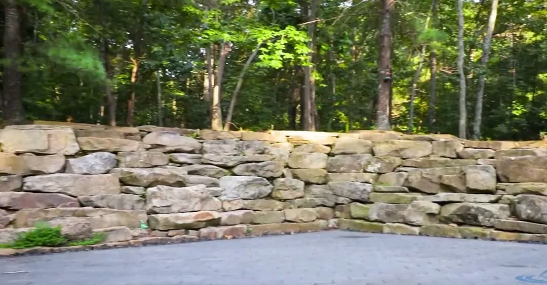 Boulder retaining wall along a driveway