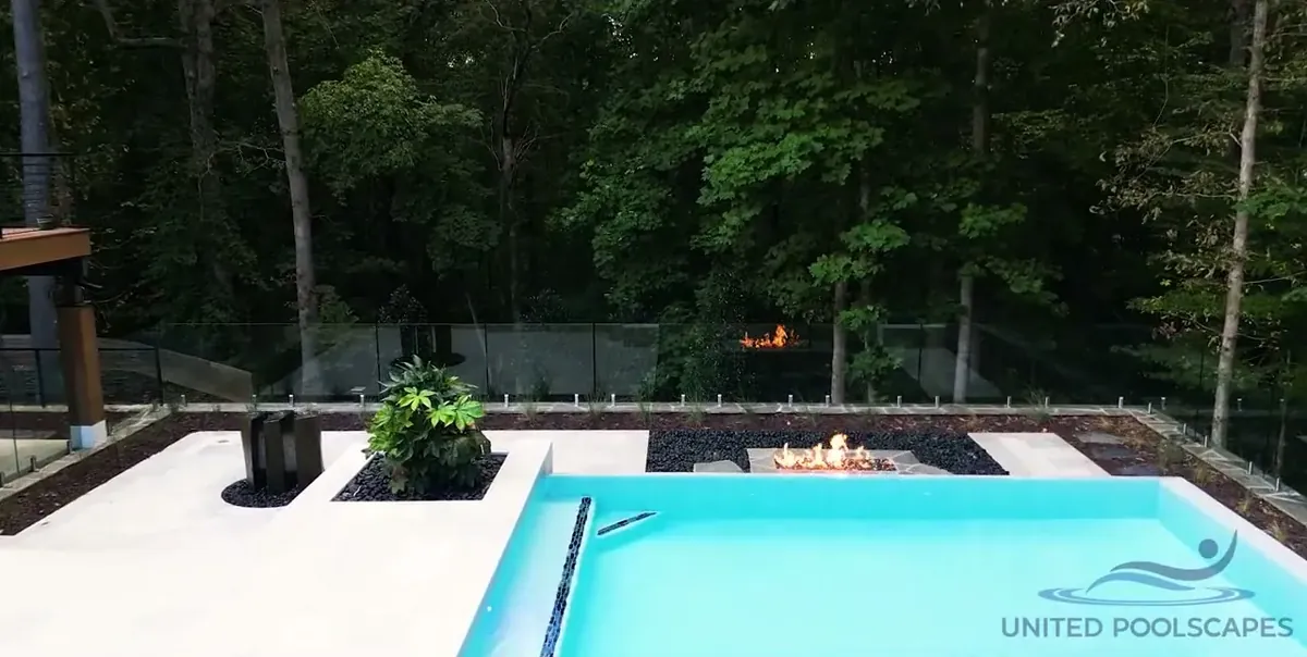 Pool with a stone deck and a fire table