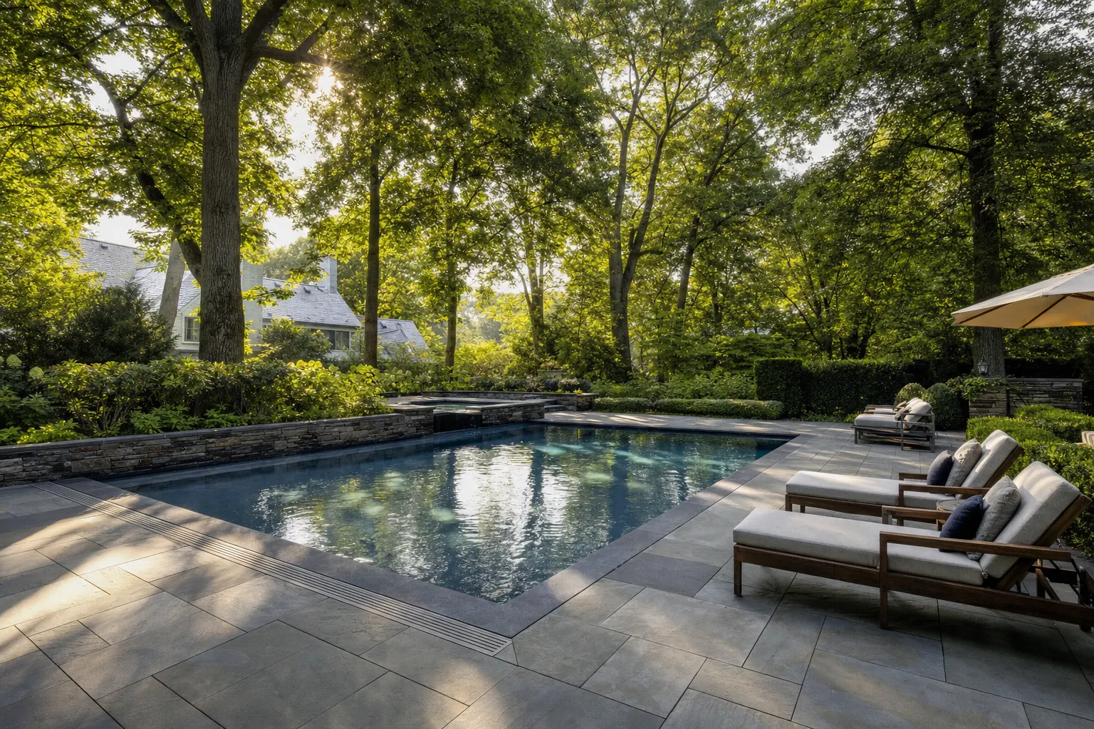 Existing pool with a rebuilt deck of large stone pavers and new coping under tall trees